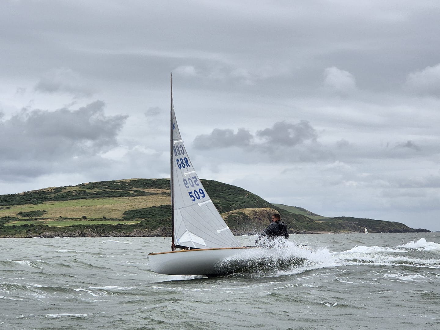 Club Commodore Scott McColm on the crest of a wave at some speed in his Finn (Photo by Richard Bishop)